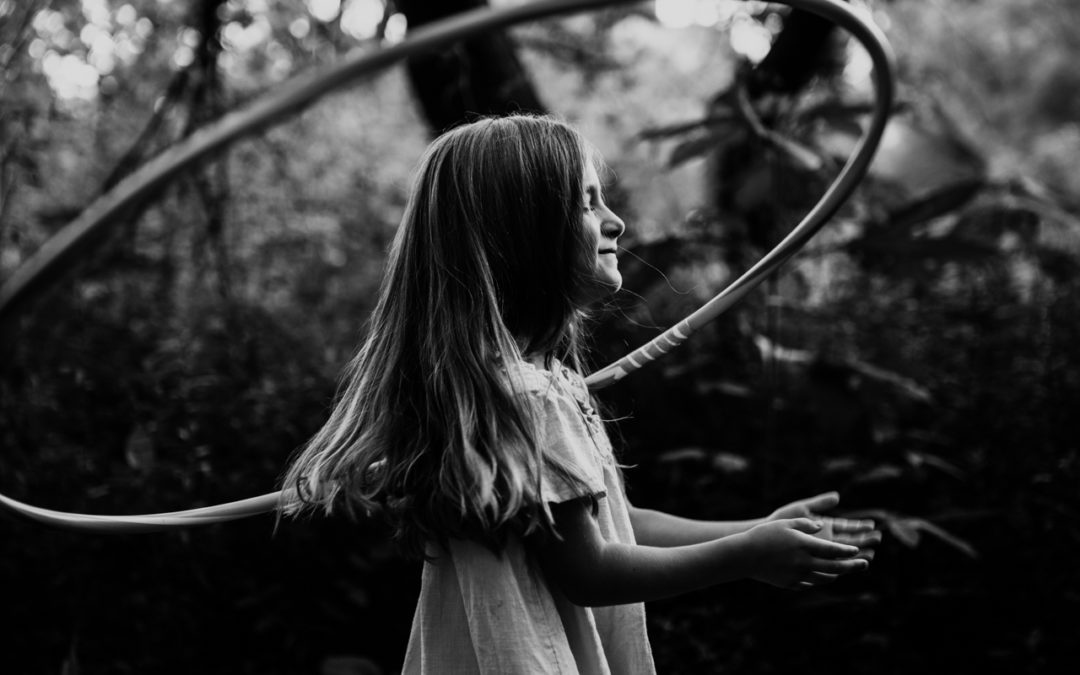 portrait of a girl hula hooping in the woods